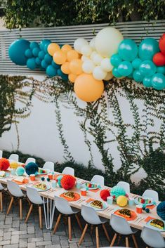 a long table with balloons and plates on it