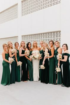 a group of women standing next to each other holding bouquets in front of a building