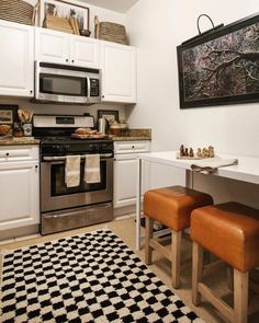 a kitchen with white cabinets and black and white rug