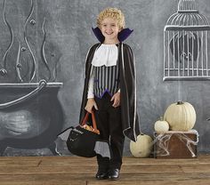 a little boy dressed up as a witch with a birdcage in the background