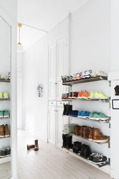 there are many pairs of shoes on the shelves in this white shoe store that is empty