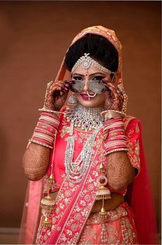 a woman in a red and gold bridal outfit is holding her hands up to her face