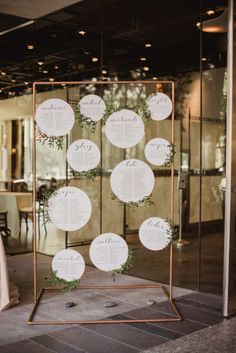 the seating chart is set up on a metal stand with greenery and white paper