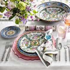 the table is set with plates, silverware and flowers in vases on it