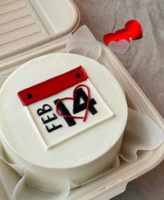 a white cake in a plastic container with red ribbon on top and the number forty four