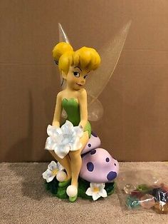 a fairy figurine sitting on top of a mushroom next to a bag of candy