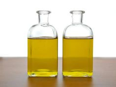 two bottles filled with oil sitting on top of a wooden table