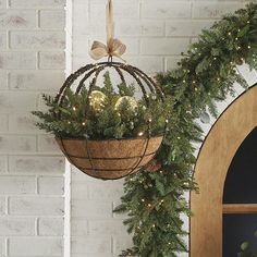 a hanging planter filled with greenery next to a wreath on a door way