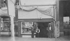 two men standing in front of a building with an american flag hanging from the roof