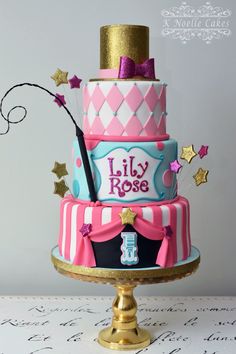 a three tiered cake decorated with pink, blue and gold