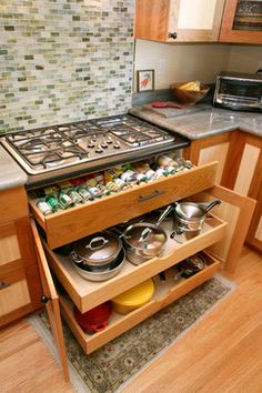 an open drawer in the middle of a kitchen with pots and pans on it