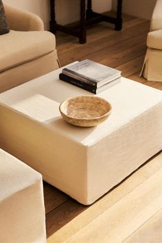 a table with a bowl on top of it in front of a couch and chair