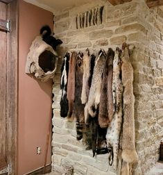 a bunch of furs hanging on a brick wall in a room with stone walls