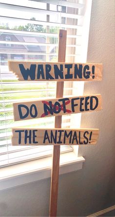 a wooden sign that says warning do not feed the animals on it in front of a window