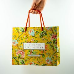 a person's hand holding a yellow shopping bag with the design archives on it