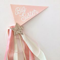 a pink and white pinwheel with the words big sister written on it next to ribbons