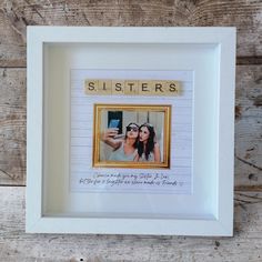 a white framed photo with the word sisters spelled in scrabble