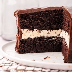 a chocolate cake with white frosting and one slice cut from it on a plate