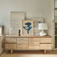 a wooden dresser sitting in a living room next to a lamp and pictures on the wall