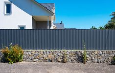 a black and white fire hydrant sitting next to a stone wall in front of a house