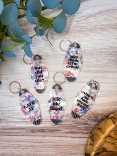 four keychains with words on them sitting next to a plant