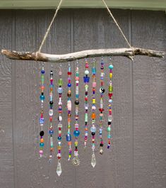 a wooden branch hanging from the side of a building with colorful beads and glass beads attached to it