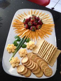 a platter with crackers, strawberries and other food items on the table