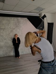 a woman is taking a photo in front of a camera while another woman stands behind her