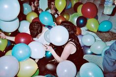 a group of people sitting on top of a couch surrounded by balloons