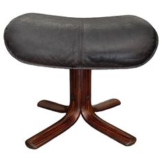 a black leather stool with wooden legs and an oval seat on the backrest is shown