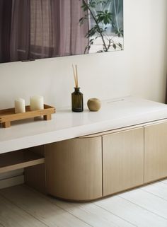 a white counter top with candles and a painting on the wall behind it in front of a window