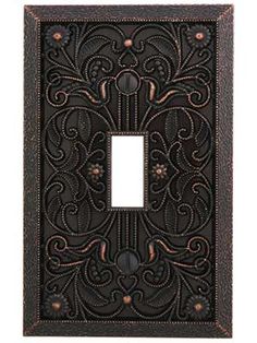 an ornate metal switch plate with a decorative design on the front and back cover,