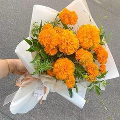 someone holding a bouquet of orange flowers in their hand