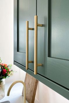 a vase with flowers sitting on top of a counter next to a cabinet and door