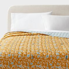 a bed with yellow and blue bedspread on top of it