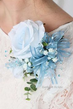 a close up of a person wearing a white dress and holding a blue flower bouquet