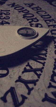 a clock sitting on top of a table covered in letters and numbers that spell out the time