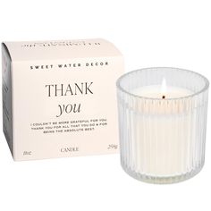 a white candle sitting in front of a box with the words thank you written on it