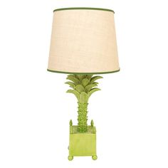 a green table lamp with a white shade on it's base and palm tree design