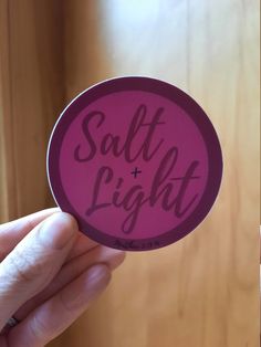 a person holding up a sticker that says salt and light on the back of it