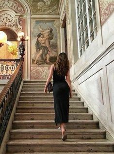 a woman is walking down some stairs in a room with paintings on the walls and ceiling