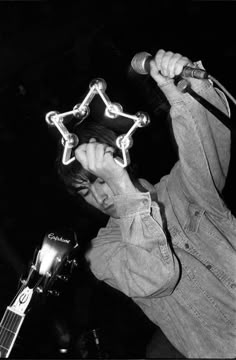 a man holding a microphone up to his face while standing in front of a guitar