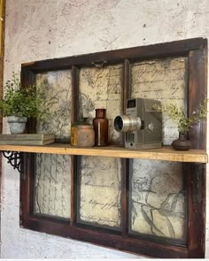 an old wooden shelf with various items on it and some plants in the window sill