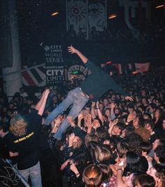 a man is in the middle of a crowd at a concert with his arms up