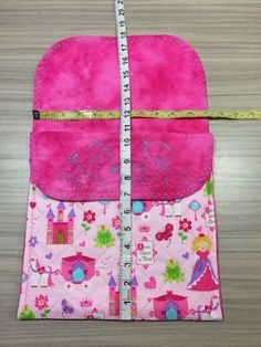 a pink purse with a measuring tape on the side and a ruler in front of it