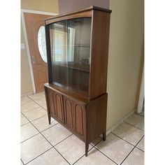 a wooden cabinet sitting on top of a tiled floor