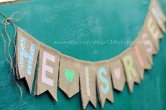 a banner that says welcome home on the side of a green door with hearts hanging from it