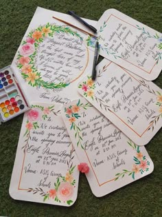 some cards with writing on them and watercolors next to it in the grass