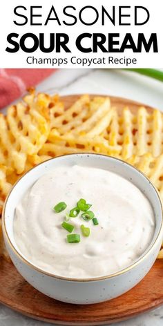 a plate topped with waffle fries covered in sour cream and garnished with green onions