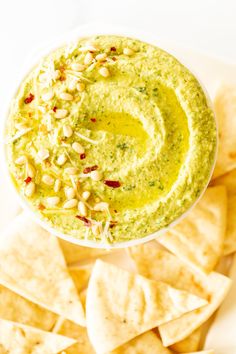 a white plate topped with tortilla chips and guacamole dipping sauce